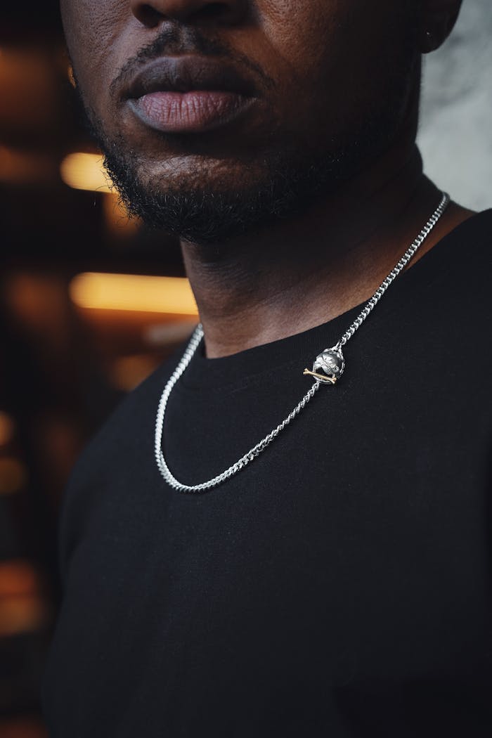 Detailed close-up of a man wearing a stylish silver necklace pendant. Modern fashion jewelry.