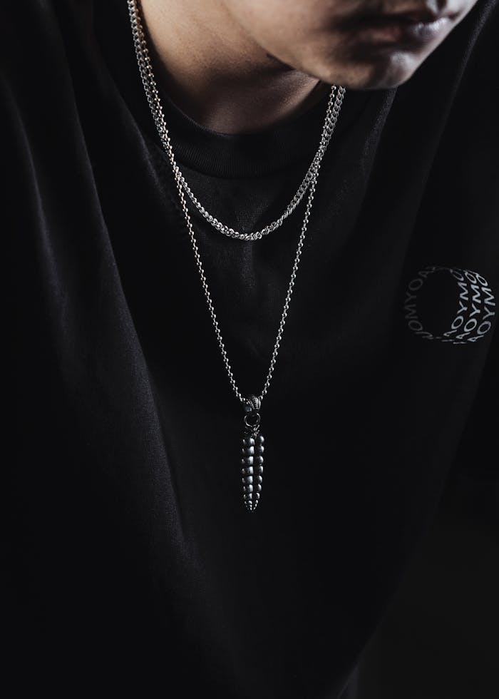 Close-up of a rattlesnake tail pendant on a black t-shirt, showcasing minimalist jewelry design.